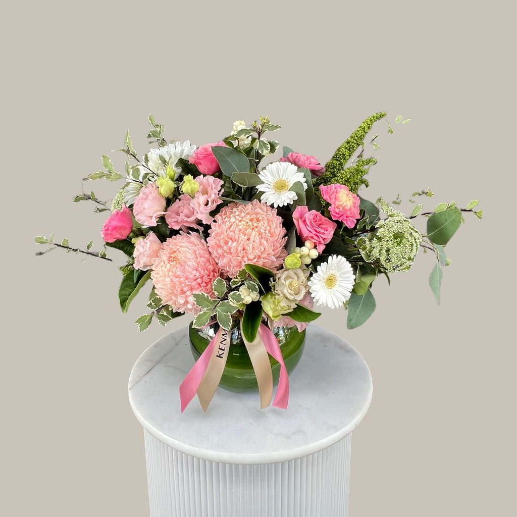 A floral arrangement in a fish bowl with a variety of flowers in pink, white, and green. Kenmore Village Florist. Brisbane Flower Delivery.