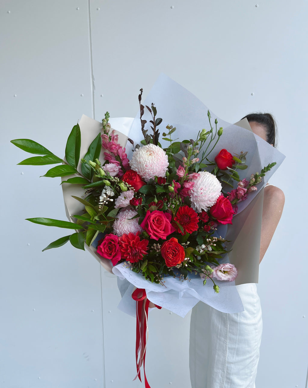 Luxury bouquet of premium roses, oriental lilies, and other seasonal blooms wrapped in white paper with a red ribbon. Kenmore Village Florist, Brisbane Flower Delivery.