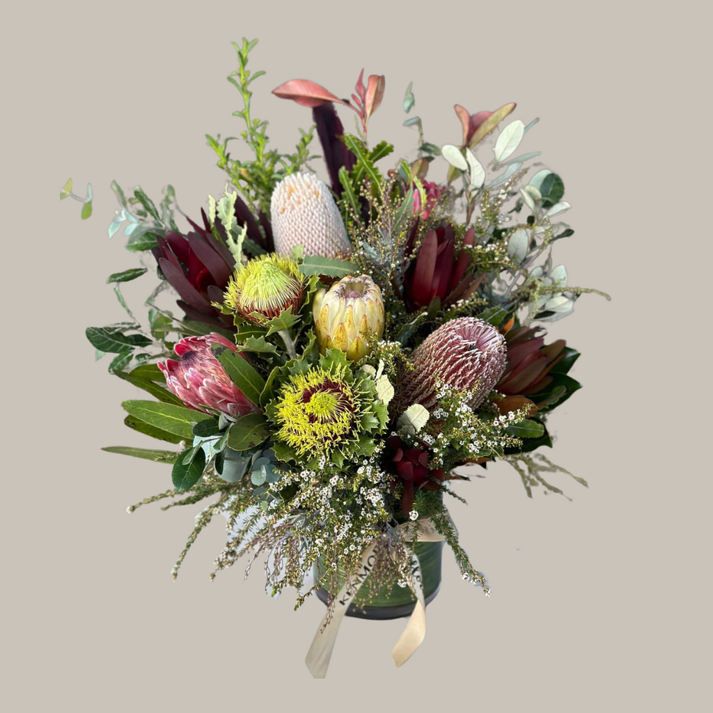 A vibrant floral arrangement featuring a variety of native Australian flowers in a mix of colors and textures, presented in a clear vase. Kenmore Village Florist. Brisbane Flower Delivery.