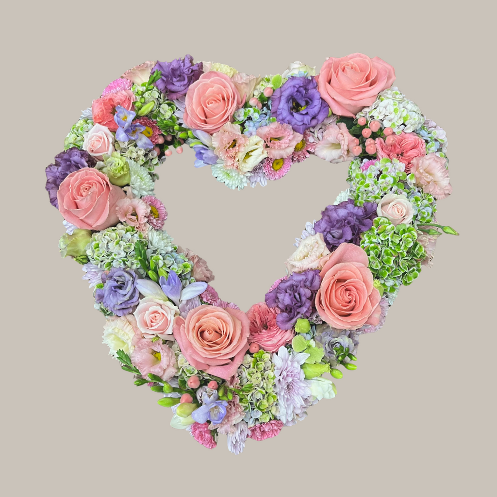 A heart-shaped floral wreath arranged with a variety of flowers in shades of pink, purple, and white. Funeral Flowers Brisbane. Kenmore Village Florist.